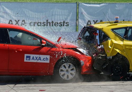 Red and yellow cars shown in a head-on collision during a crash test for safety evaluation.